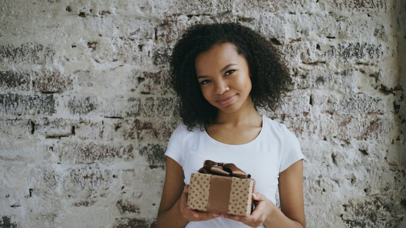 A young woman holding a small gift box