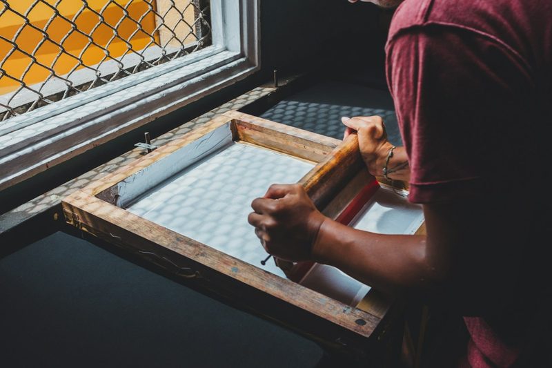Hands screen printing a design